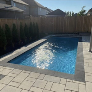 Small backyard pool with stone paver surround